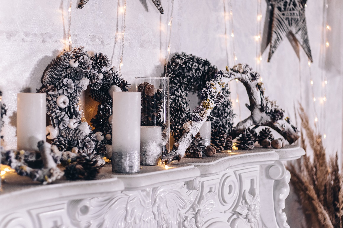 Festive New Year's white fireplace with candles and decorative wreaths of cones
